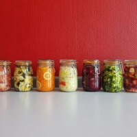 Sju glass med fargerike grønnsaker og kål til fermentering